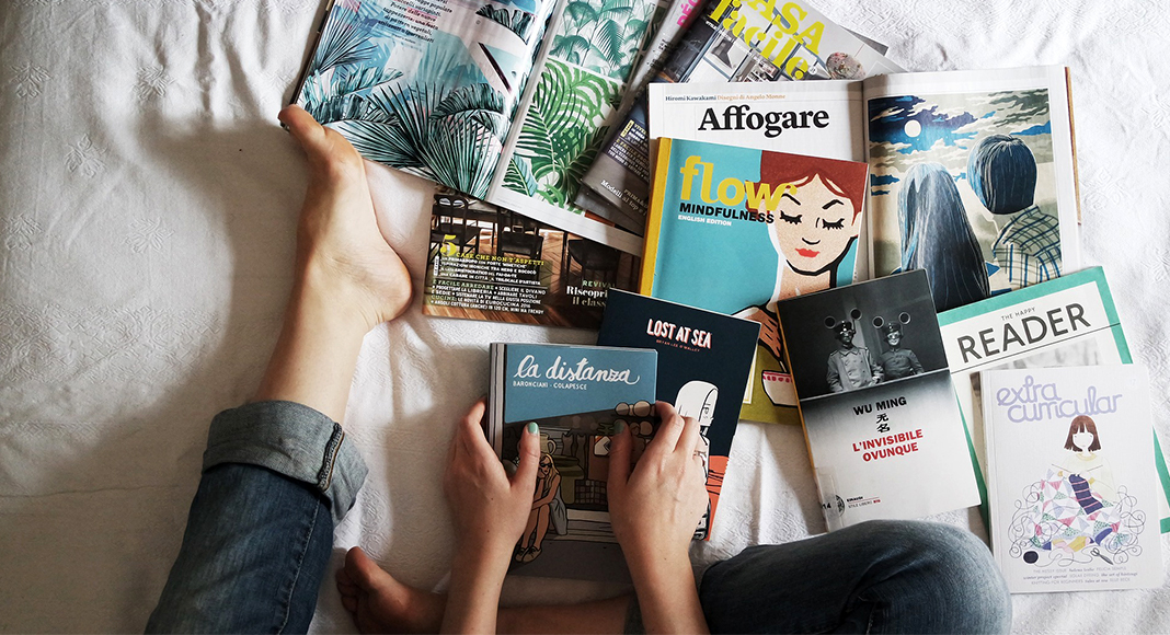 Bild Person sitzt mit verschiedenen Büchern und Broschüren auf dem Bett.